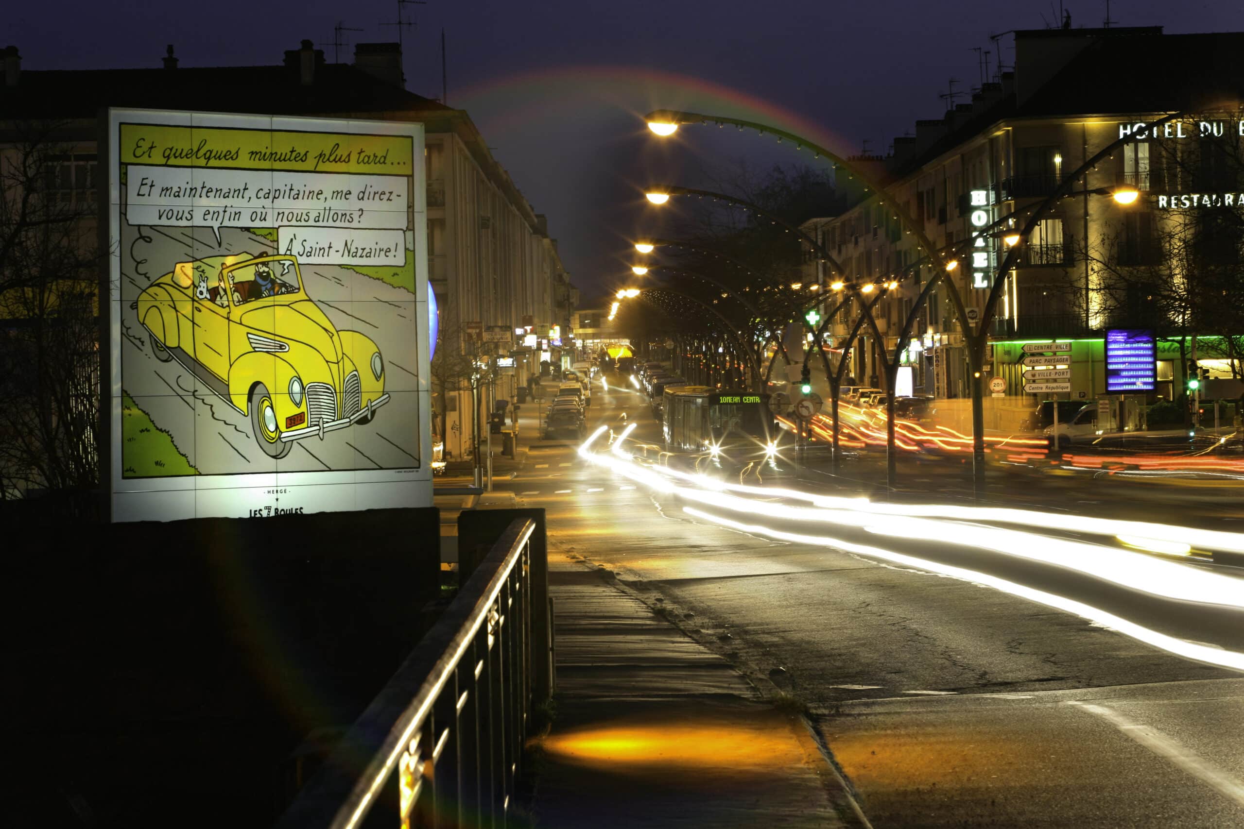 Photo de saint nazaire la nuit, avenue de la République, paysage urbain, lumieres artificielles, effets lumineux, affiche de Tintin. circulation nocturne dans la ville.